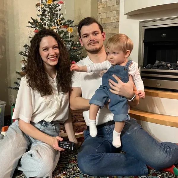 Tim with his wife and Timofey on a rug by the Christmas tree.